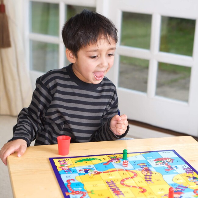 Junge, der am Tisch an einem Spielbrett sitzt