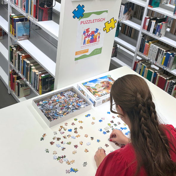 Frau beim Puzzeln in Bücherei